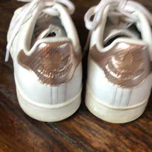 Stan Smith all white tennis shoes with rose gold accent.